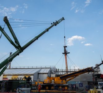 A large crane starts to lift the foremast off HMS Victory