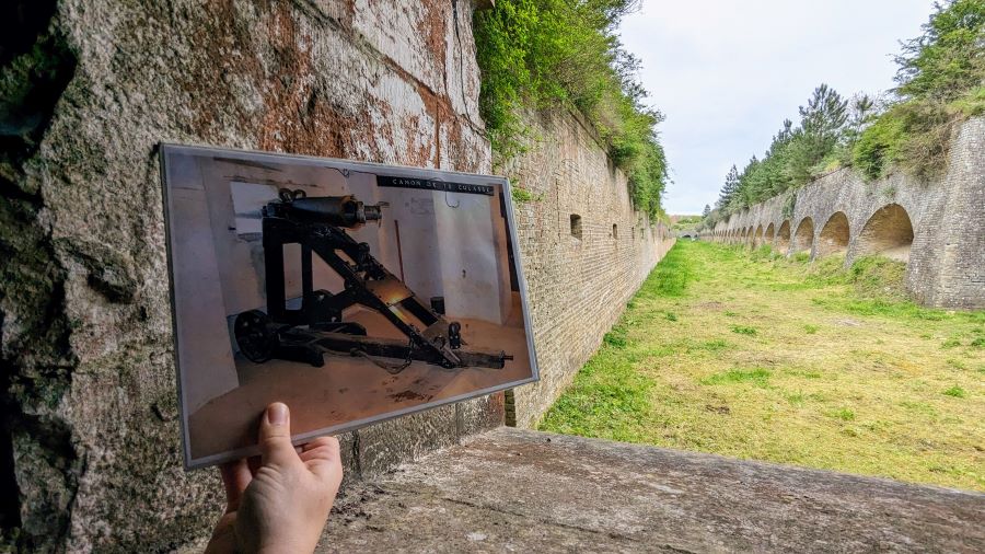 A photo is held up to show a cannon in this location