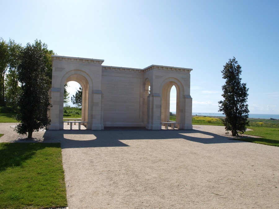 A white stone memorial wall with gateways & pillars