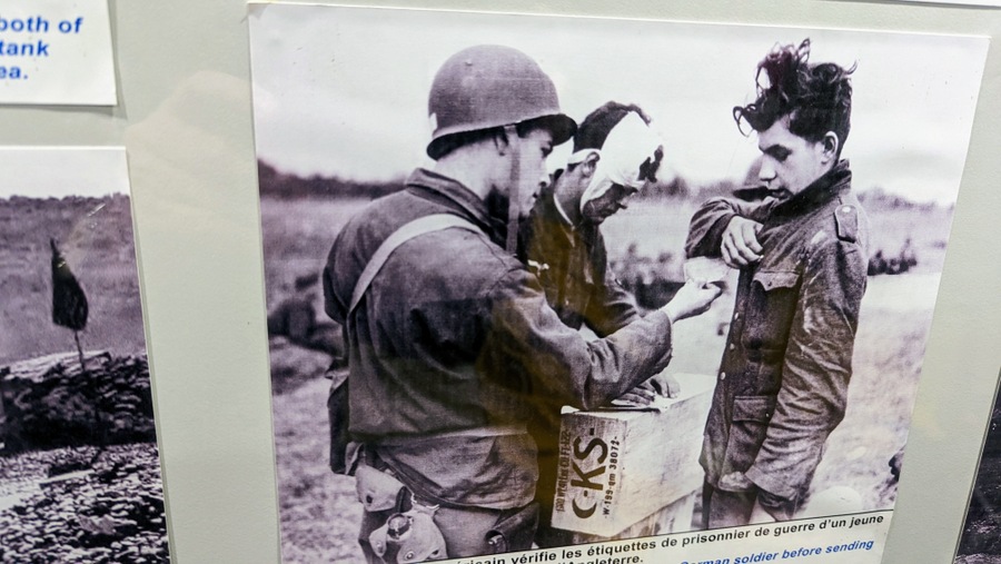 Photo of a very young German POW being searched by a GI