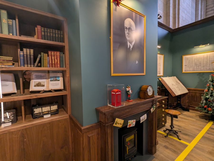 Display replica of the BPS architect's office, with a fireplace and portrait above it, book shelves and a small red pillar box on the mantlepiece
