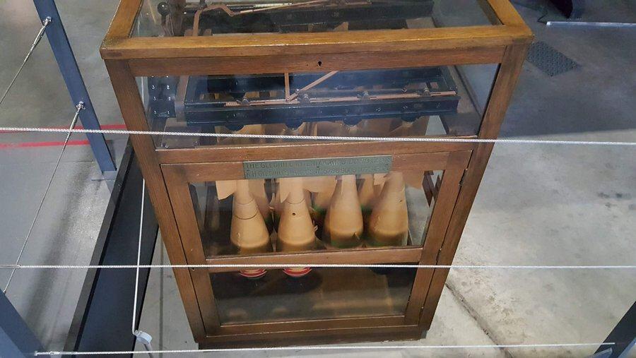 Glass display cabinet with a number of small bombs hanging from a complicated release mechanism