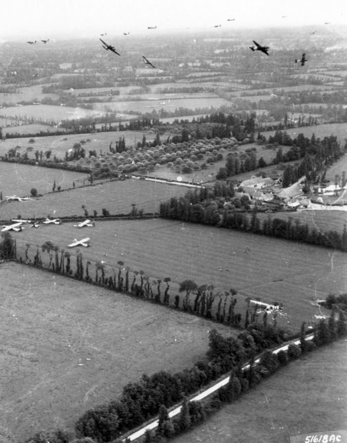 Black & white photo of gliders circling in the sky and a number already landed or crashed in the fields below.