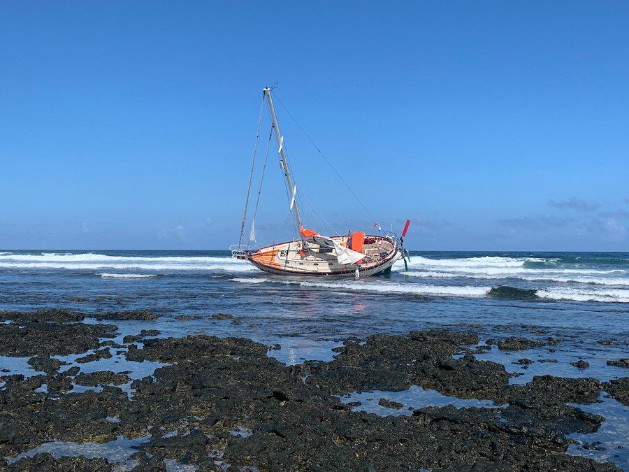 Guy De Boer's GGR yacht 'Spirit'lies at an angle on the rocks in the surf