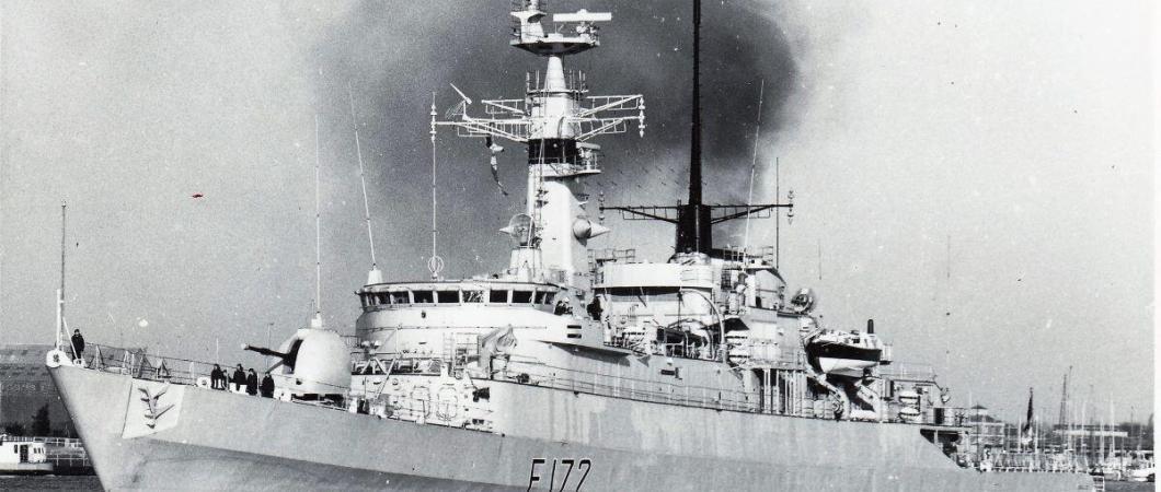 B&W photo of the destroyer, HMS Ambuscade, steaming out of a harbour