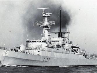 B&W photo of the destroyer, HMS Ambuscade, steaming out of a harbour