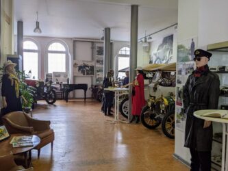 A large hall with classic cars and elegant mannequins in 20th century clothes