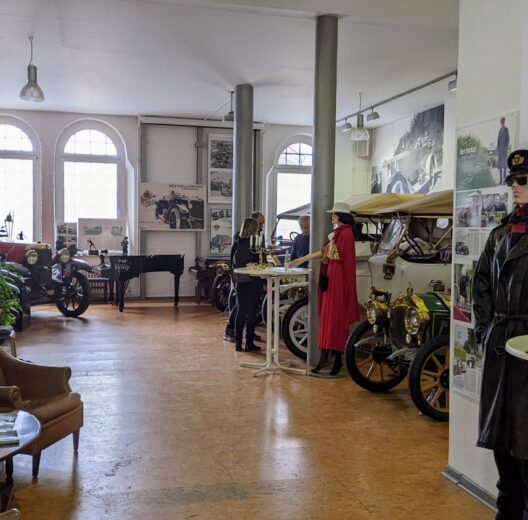 A large hall with classic cars and elegant mannequins in 20th century clothes