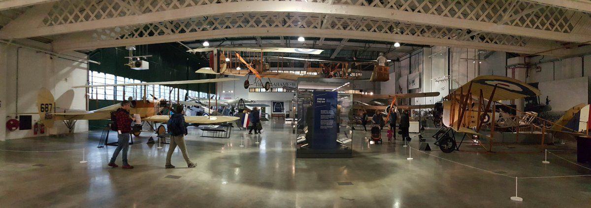 A hanger full of WW1 biplanes on the floor and suspended in the air.