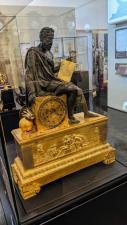 A large brass mantelpiece clock with Galileo sitting on it