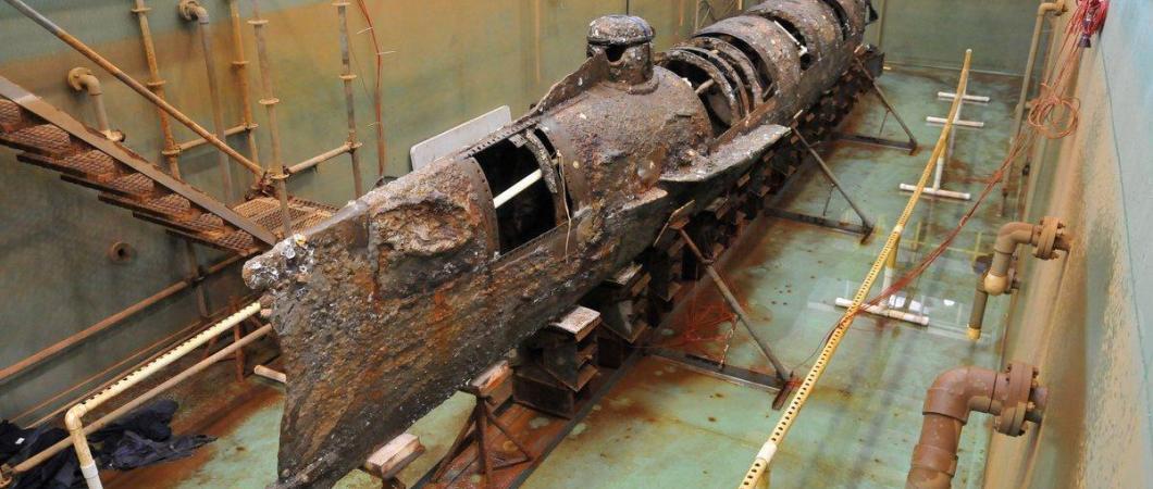 The Hunley submarine looking brown & rusty with some panels missing rests in her tank without water