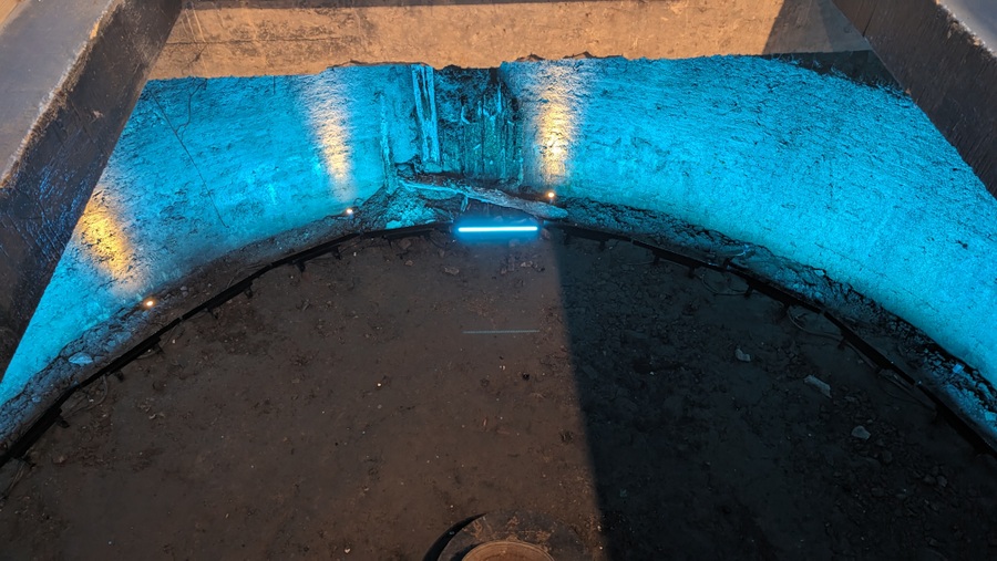 A large circular brick cistern-like hole with blue lighting