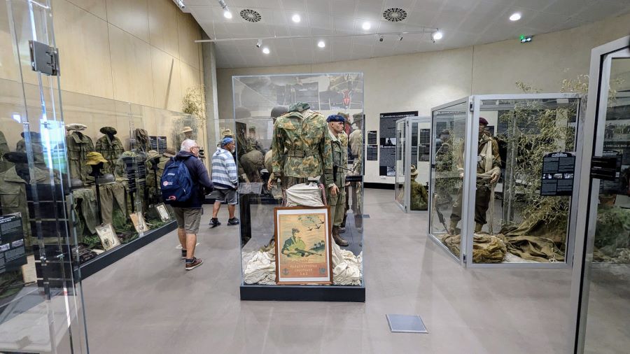 A pair of visitors wander through a number of glass display cases containing uniformed mannequins