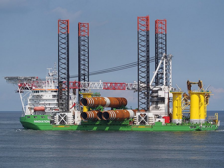 a Green ship with four black pylons for jacking up, and crrying a set of yellow tubes