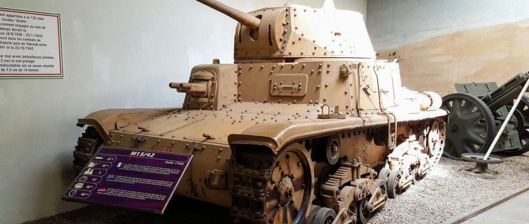 Old fashioned medium tank with riveted armour and painted in light brown desert camouflage