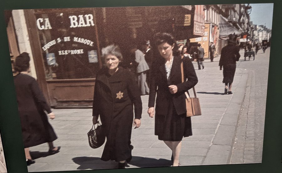 Two women on a Paris street. One of them has a Star of David on her coat