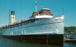 Old-fashioned, white hulled steamship alongside a pier