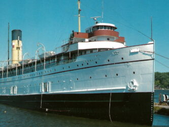 Old-fashioned, white hulled steamship alongside a pier