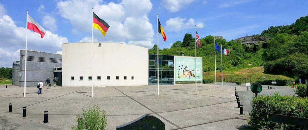 Entrance building on a sunny day with flags outside and the dome itself in the background