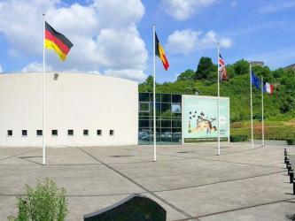 Entrance building on a sunny day with flags outside and the dome itself in the background