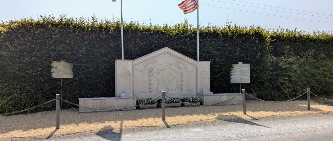 A large stone monument with flags by the side of the road
