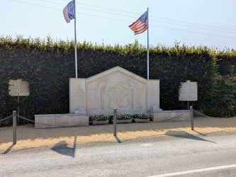 A large stone monument with flags by the side of the road