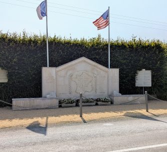 A large stone monument with flags by the side of the road