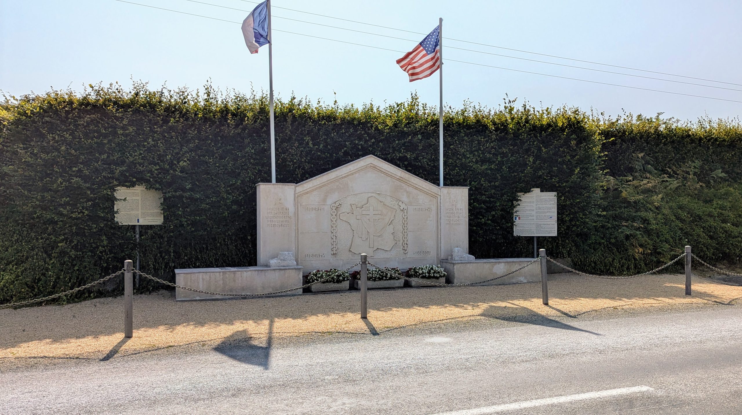 A large stone monument with flags by the side of the road