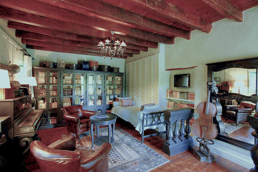 Richly furnished room with wooden beams, glass-panelled bookcases and a brown leather armchair