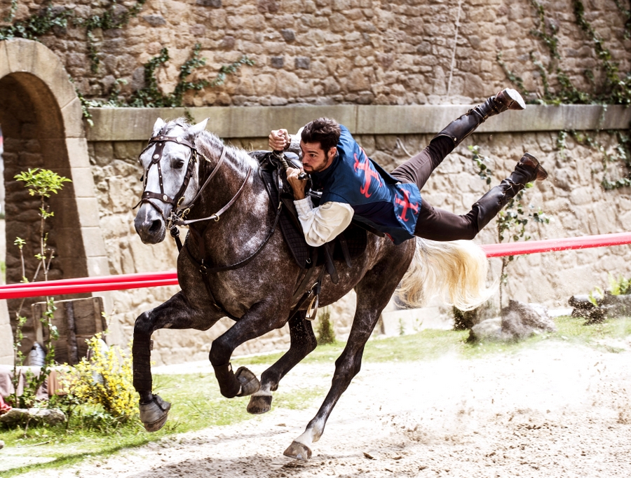 A horse rider gallops riding flat on the horse's back with his legs flying behind him