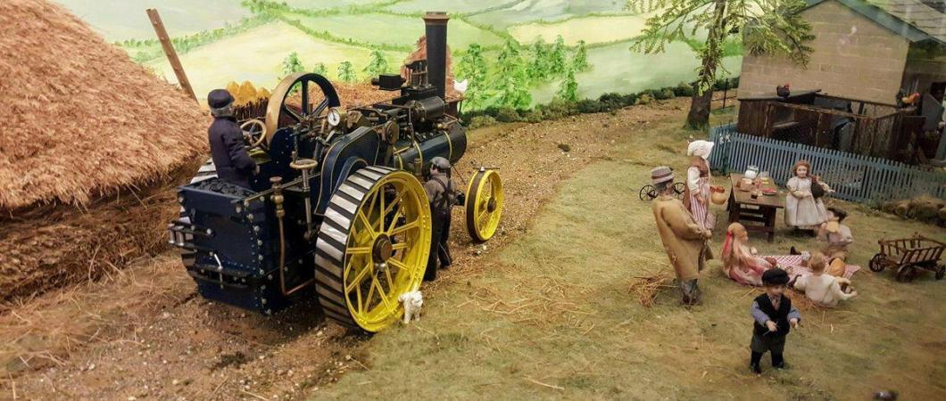 Model diorama rural scene with two labourers attending a steam traction engine and a family playing nearby