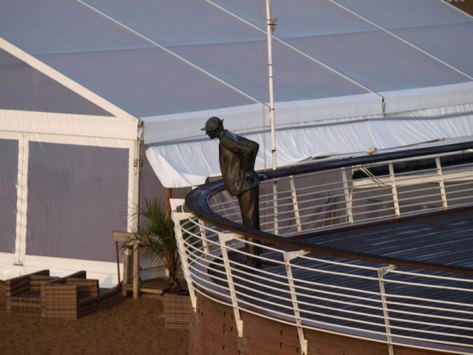 A bronze statue of M. Hulot in characteristic pose on the boardwalk above the beach