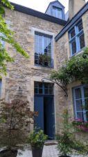 Courtyard of Maison Saint-Pierre, a stone walled house with blue window frames.