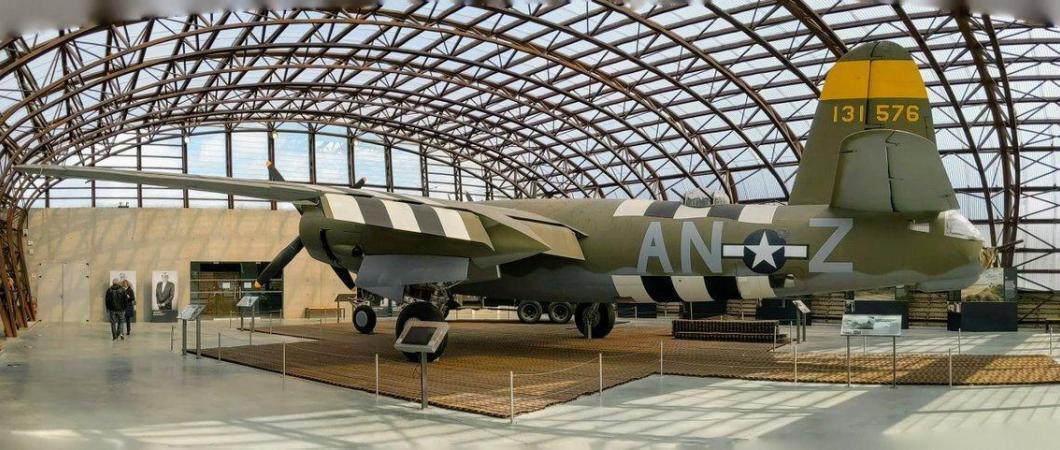 A green camouflaged twin-engined bomber in a glass hanger