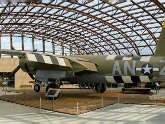 A green camouflaged twin-engined bomber in a glass hanger