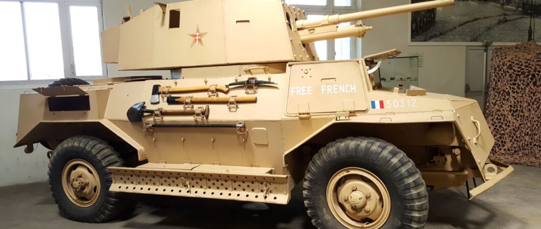 A sand brown four-wheel drive armoured scout car in Free French colours
