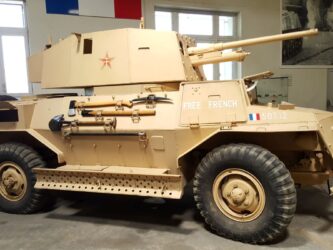 A sand brown four-wheel drive armoured scout car in Free French colours