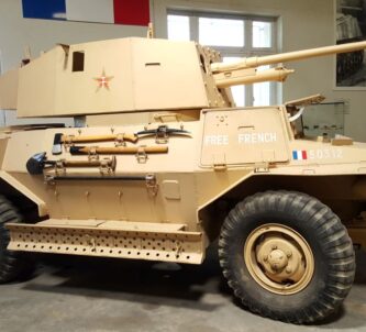 A sand brown four-wheel drive armoured scout car in Free French colours