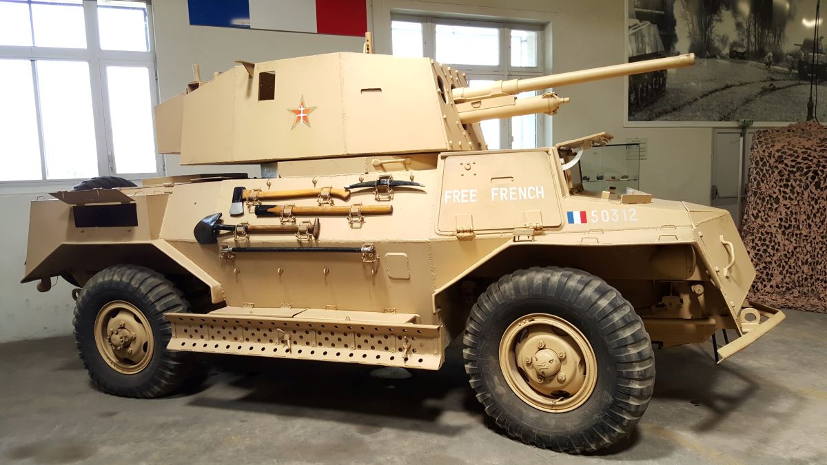 A sand brown four-wheel drive armoured scout car in Free French colours