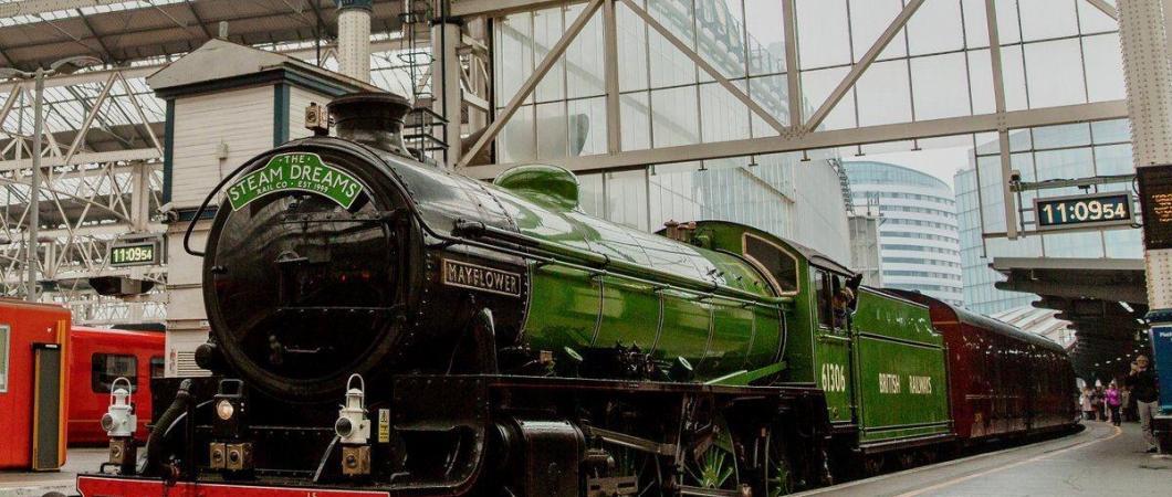 Classic steam locomotive in glistening green livery alongside the platform