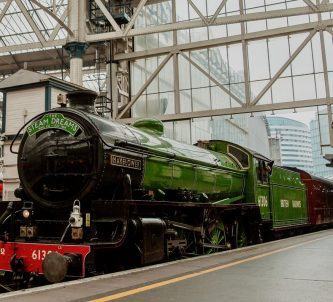 Classic steam locomotive in glistening green livery alongside the platform