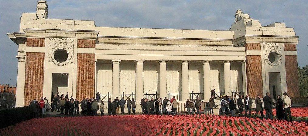 People queue to enter the classic mausoleum-like building with a field of red poppies in the foreground
