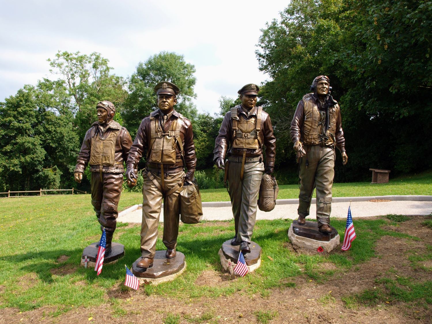 Four life-size bronze statues of USAAF airmen striding towards the camera on a grassy hill