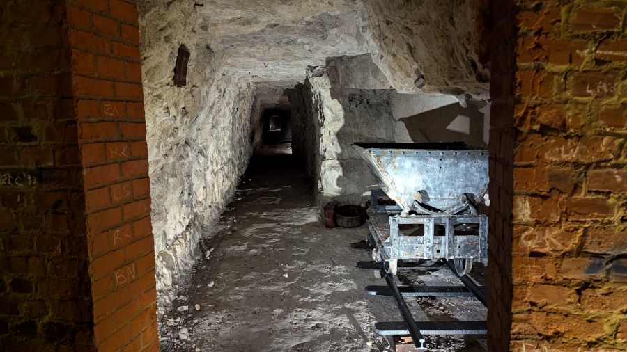 A side gallery has an abandoned mining truck on rails