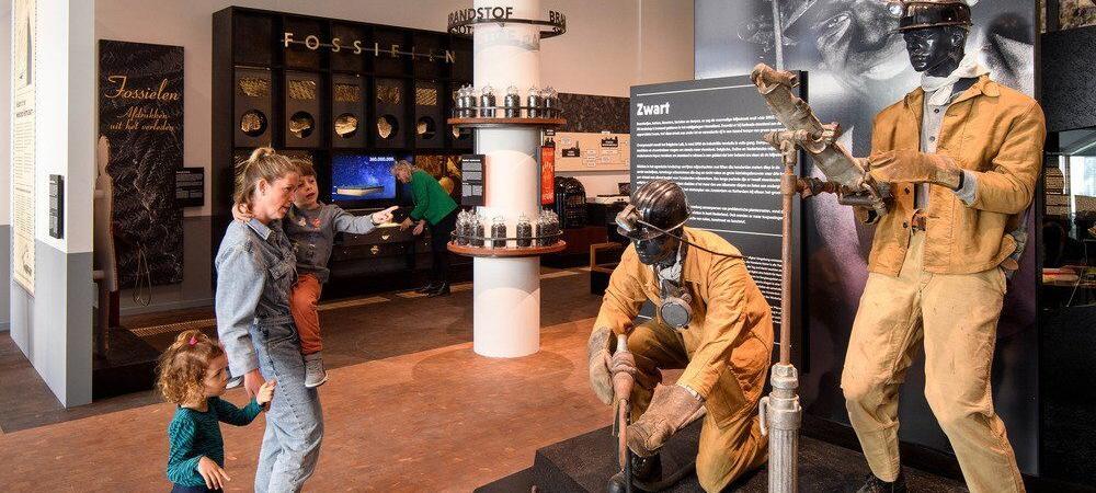 Visitors look at two miner mannequins in orange overalls