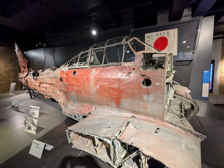 The wrecked fuselage with patches of red paint, of a Japanese WW2 Zero, minus engine, wings or tailplane.