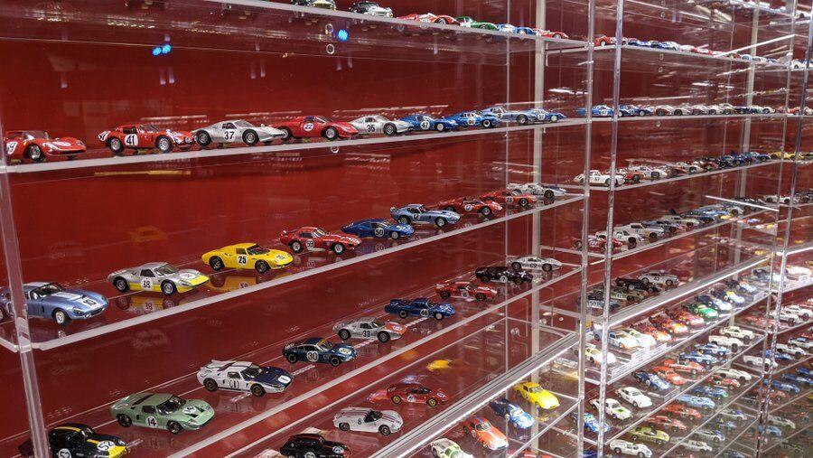 Glass fronted cabinet with red shelves full of model cars