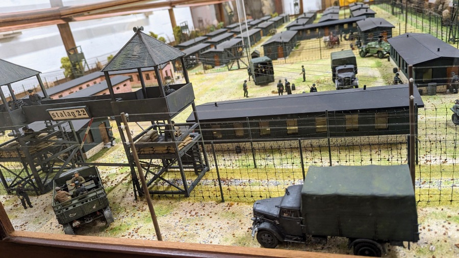 A detailed model of a German Prisoner of War camp. The photo covers the front gates where new prisoners are arriving in trucks