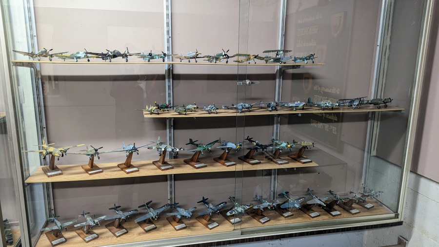 A glass display cabinet with shelves full of model aircraft