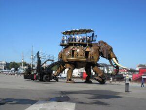 A giant mechanical elephant with passengers riding on a platform on its back
